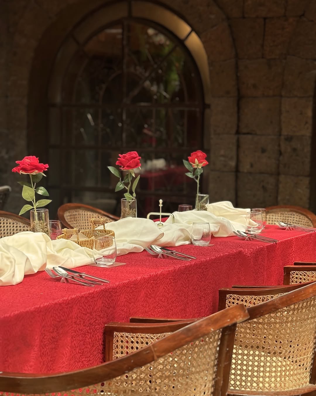 Intimate AMBAI table set with red roses under stone arch